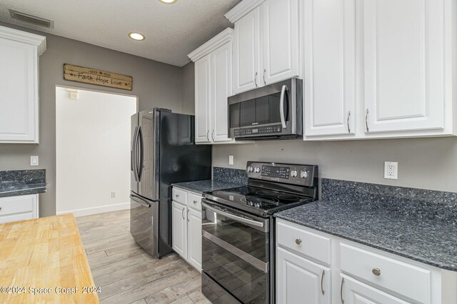 kitchen featuring light hardwood / wood-style flooring, a textured ceiling, stainless steel appliances, and white cabinetry