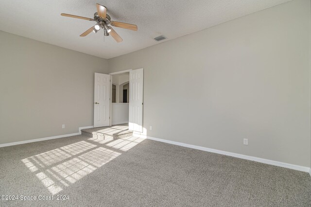 empty room featuring ceiling fan, carpet floors, and a textured ceiling