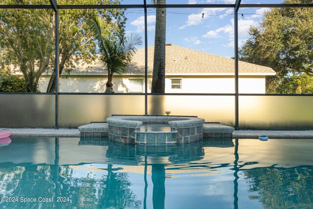 view of swimming pool featuring glass enclosure and an in ground hot tub