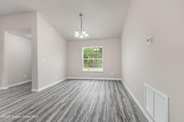 spare room with hardwood / wood-style floors and an inviting chandelier