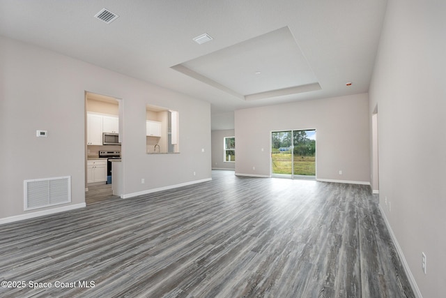 unfurnished living room featuring dark hardwood / wood-style floors and a tray ceiling