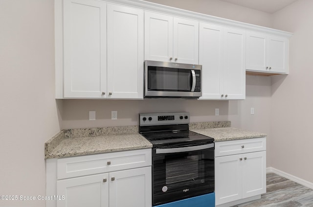 kitchen with range with electric stovetop, light hardwood / wood-style floors, white cabinets, and light stone countertops