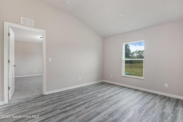 spare room featuring vaulted ceiling and wood-type flooring