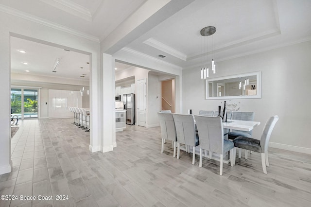 dining room with light wood-type flooring, crown molding, and a tray ceiling