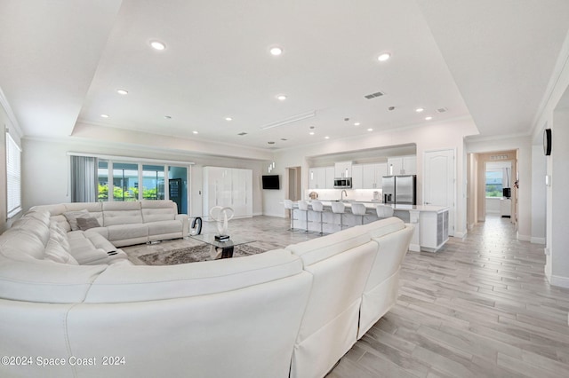 living room with light wood-type flooring, crown molding, and a wealth of natural light