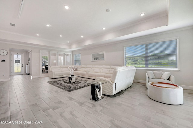 living room with ornamental molding, a raised ceiling, and light hardwood / wood-style flooring