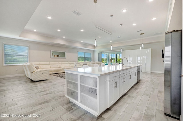 kitchen featuring an island with sink, white cabinetry, hanging light fixtures, and sink