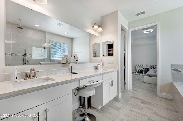 bathroom with a tile shower, vanity, and hardwood / wood-style floors