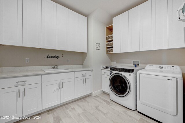 laundry area featuring light hardwood / wood-style floors, separate washer and dryer, sink, and cabinets