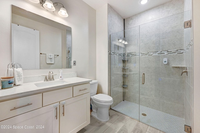 bathroom featuring hardwood / wood-style flooring, a shower with door, vanity, and toilet