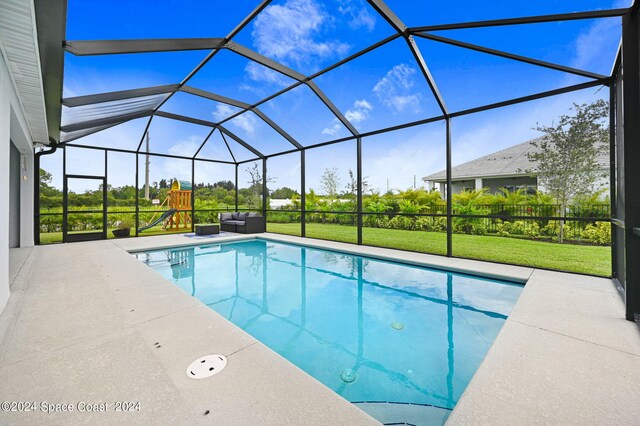 view of pool with glass enclosure, a yard, and a patio