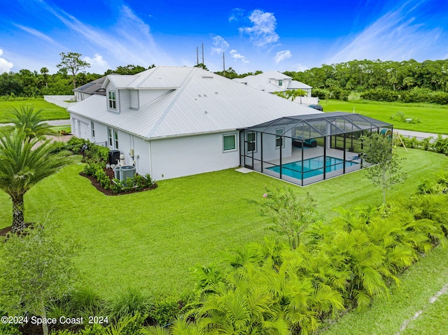 rear view of property with a lawn, cooling unit, a patio, and glass enclosure