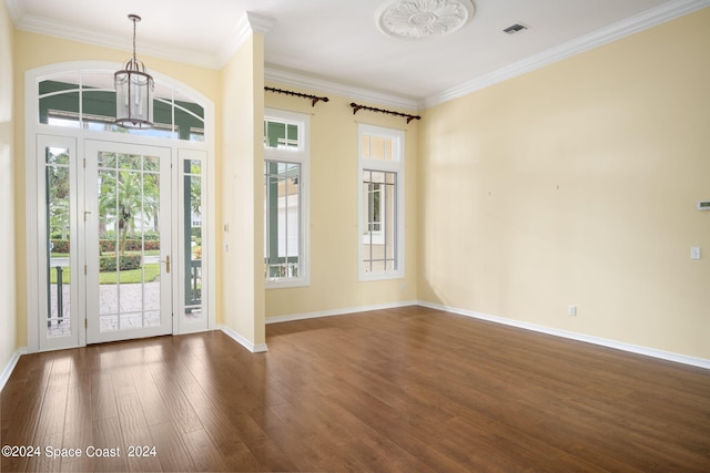 foyer with ornamental molding, a notable chandelier, and dark wood-type flooring