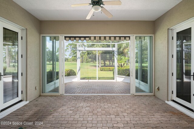 unfurnished sunroom with ceiling fan