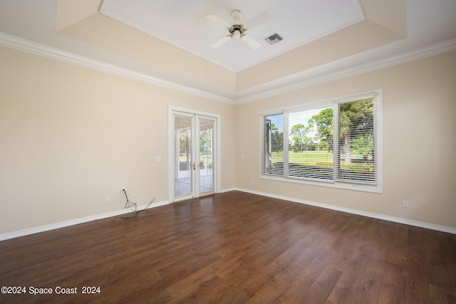 unfurnished room featuring a tray ceiling, ornamental molding, dark wood-type flooring, and ceiling fan