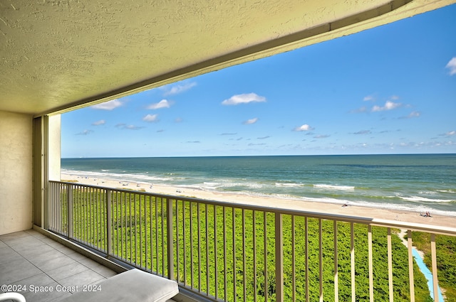 balcony featuring a beach view and a water view