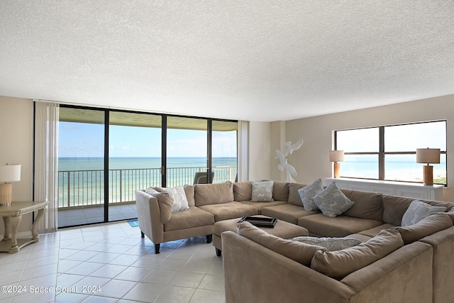 living room with a wealth of natural light, a water view, and light tile patterned floors