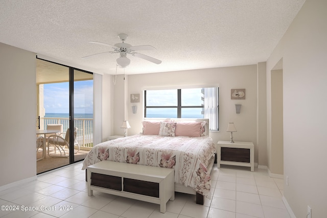 bedroom with access to outside, ceiling fan, light tile patterned floors, a textured ceiling, and a water view