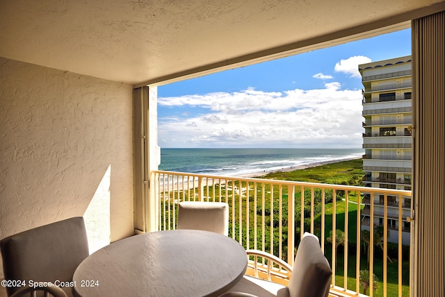 balcony with a water view and a view of the beach