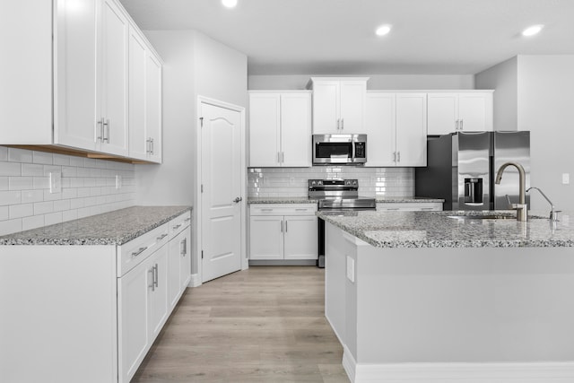 kitchen featuring appliances with stainless steel finishes, tasteful backsplash, light hardwood / wood-style floors, sink, and white cabinetry