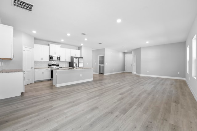 kitchen featuring appliances with stainless steel finishes, white cabinetry, a center island with sink, and light hardwood / wood-style floors