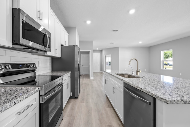 kitchen featuring white cabinets, an island with sink, stainless steel appliances, and sink