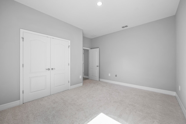 unfurnished bedroom with light carpet and a closet