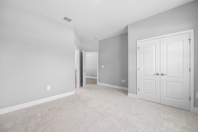 unfurnished bedroom with light colored carpet and a closet