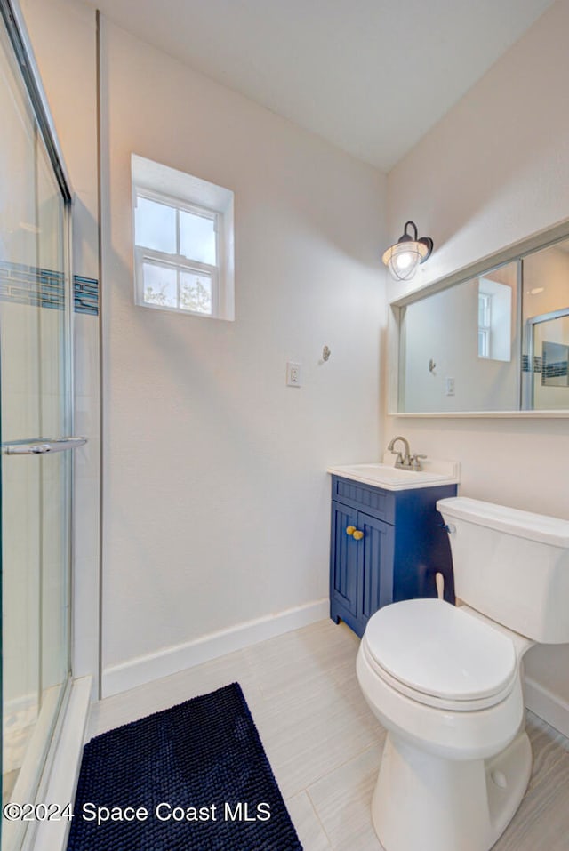 bathroom with vanity, toilet, and a shower with door