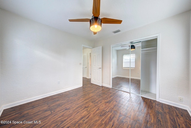 unfurnished bedroom featuring dark wood-type flooring, ceiling fan, and a closet