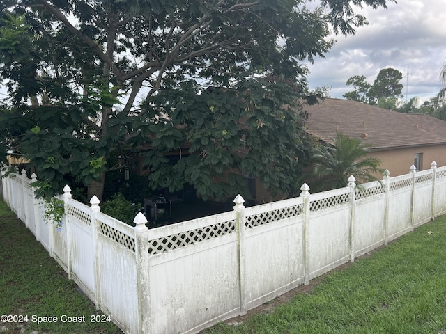 view of side of home with a lawn, fence private yard, and a shingled roof