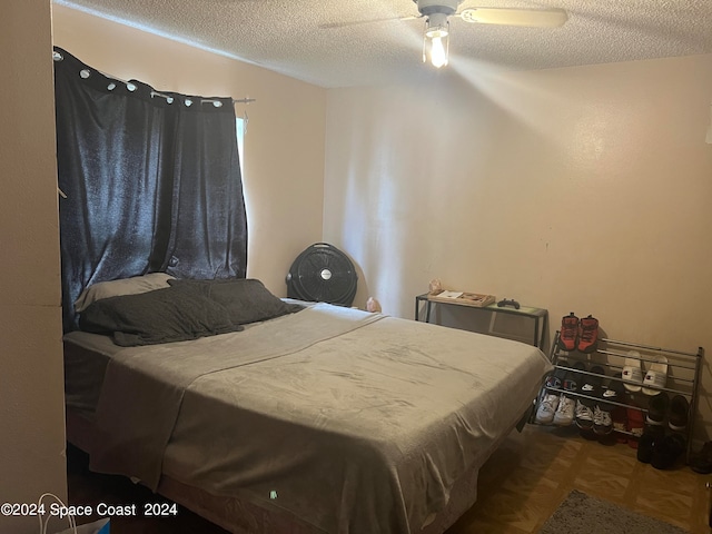 bedroom featuring ceiling fan, a textured ceiling, and parquet flooring