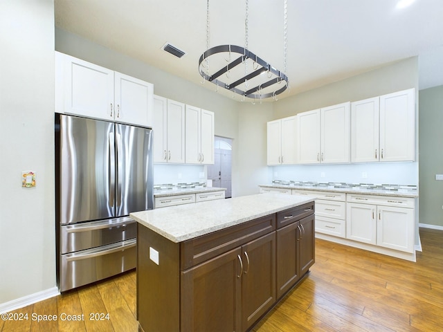 kitchen featuring hardwood / wood-style floors, stainless steel fridge, and white cabinets