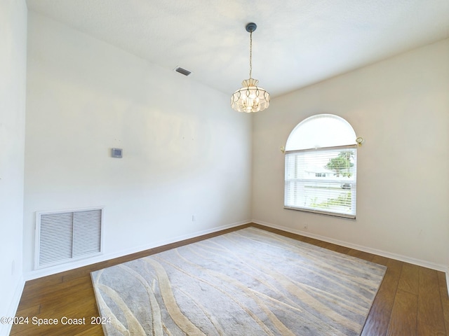 spare room with dark hardwood / wood-style flooring and a chandelier