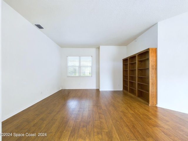 spare room featuring wood-type flooring and a textured ceiling