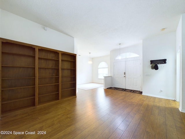 unfurnished living room featuring a textured ceiling and dark hardwood / wood-style floors