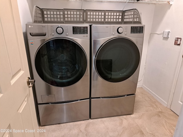 clothes washing area featuring light tile patterned floors and washer and clothes dryer