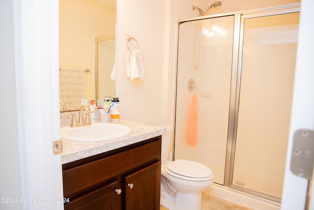 bathroom with toilet, a shower with door, and vanity