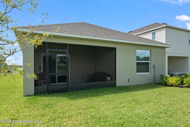 rear view of house featuring a yard, a sunroom, and central air condition unit