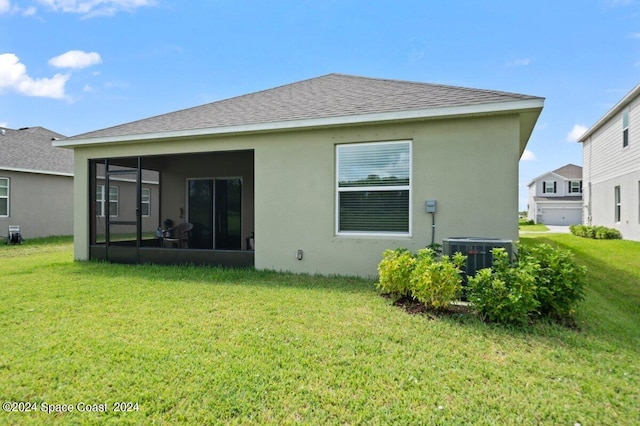 rear view of house with a sunroom, a yard, and cooling unit