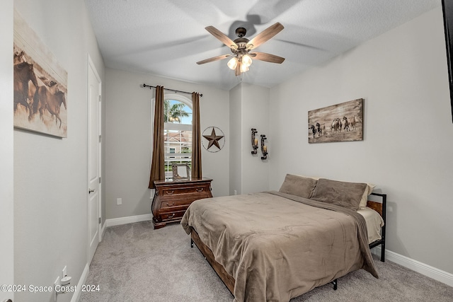 carpeted bedroom featuring ceiling fan and a textured ceiling