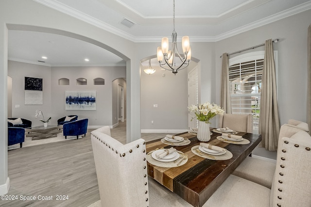 dining area with light hardwood / wood-style floors, crown molding, and an inviting chandelier