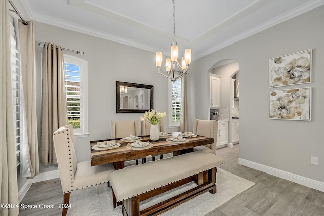 dining area featuring crown molding, an inviting chandelier, and light hardwood / wood-style floors