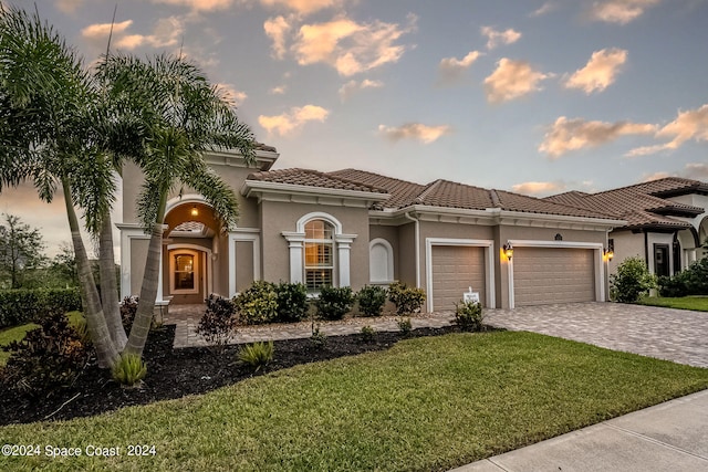 mediterranean / spanish-style home with a garage and a lawn