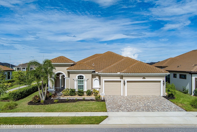 mediterranean / spanish home featuring a front yard and a garage