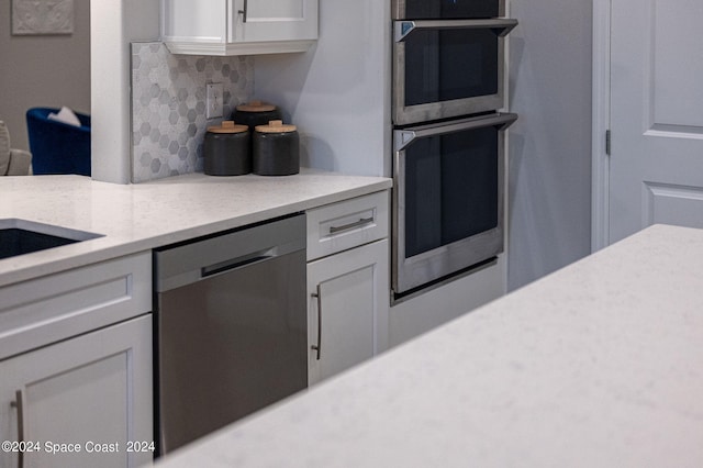 kitchen featuring appliances with stainless steel finishes, decorative backsplash, and white cabinets