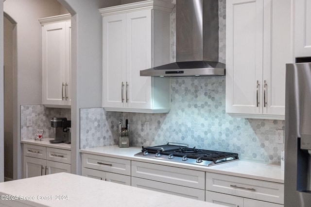 kitchen featuring white cabinets, backsplash, and wall chimney range hood