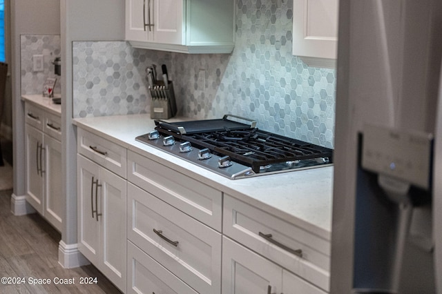 kitchen featuring stainless steel gas stovetop, hardwood / wood-style floors, and white cabinetry