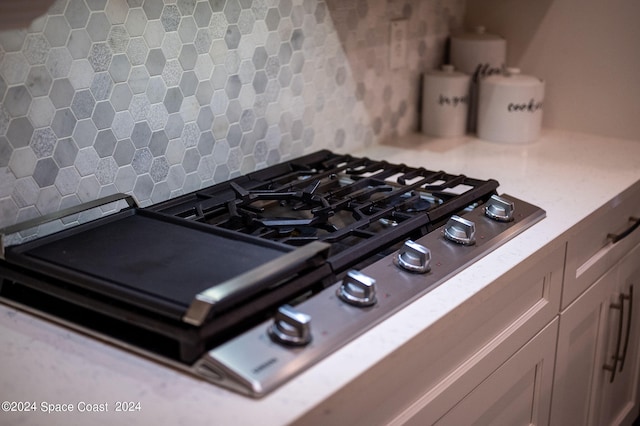 interior details with decorative backsplash and stainless steel gas cooktop