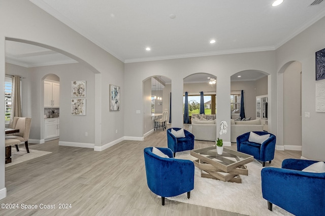 living room with crown molding, plenty of natural light, and light hardwood / wood-style flooring